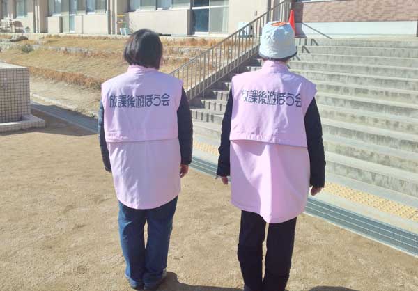 背中に団体名を名入れしたベストを着用する様子